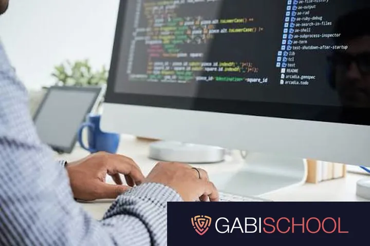 A Gabi School student writes code at a desktop computer, with the Gabi School logo