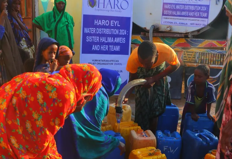 Women and children fill jerry cans from a HARO water tanker in Eyl, 2024