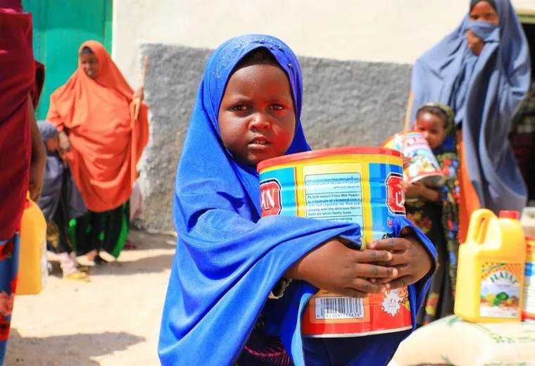 A girl holds a tin of cooking oil from her family’s HARO food package in Eyl, 2024