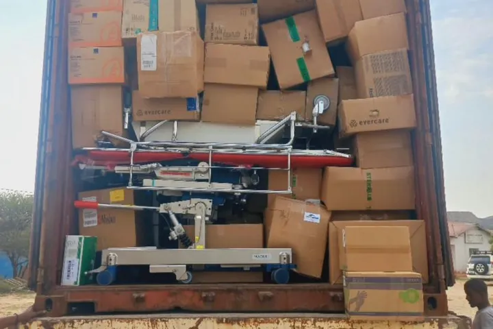 A shipping container packed with boxes of medical supplies and a hospital bed