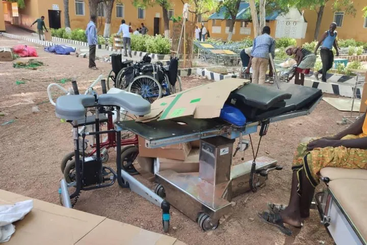 An operating table and wheelchairs unloaded in a hospital courtyard