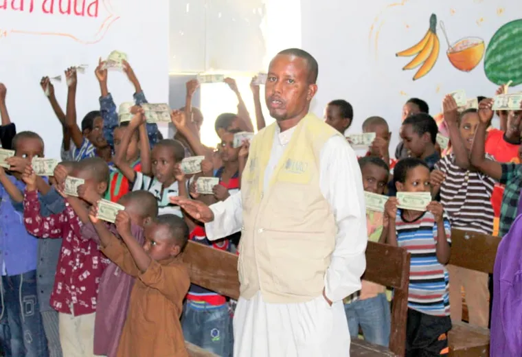 Boys hold up Eid gifts in a decorated hall during the HARO orphan Eid distribution in Qardho, 2018