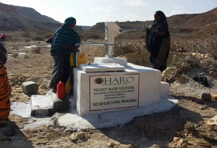 Women pump water into jerry cans at the first HARO shallow well, Tuur village, Eyl district, 2018
