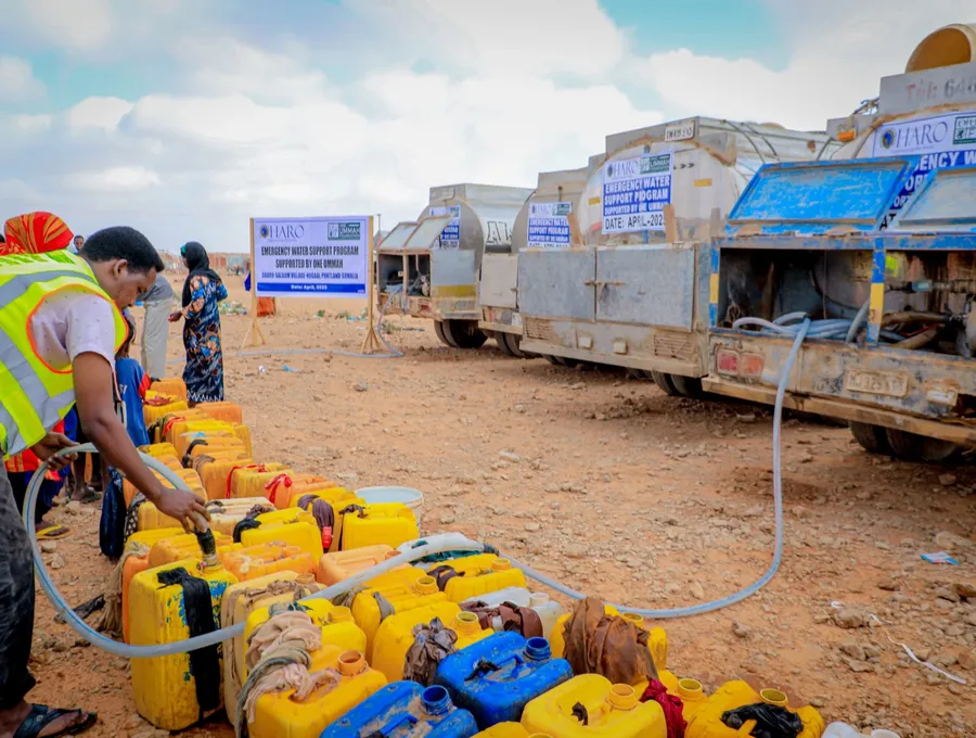 A HARO worker fills rows of jerry cans from emergency water tankers in Daaru-Salaam village, Nugaal, 2025