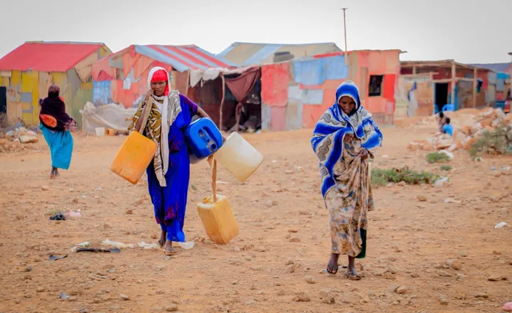 Two women carry water containers back through their neighbourhood in Somalia